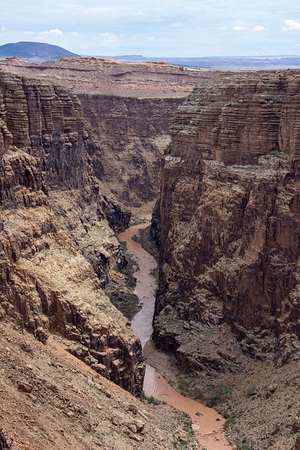 ccanyonlands_river_canyon_top Landscape of the Colorado and Green Rivers meeting deep in Canyonlands National Park, turquoise waters and red sandstone cliffs under sunlight.