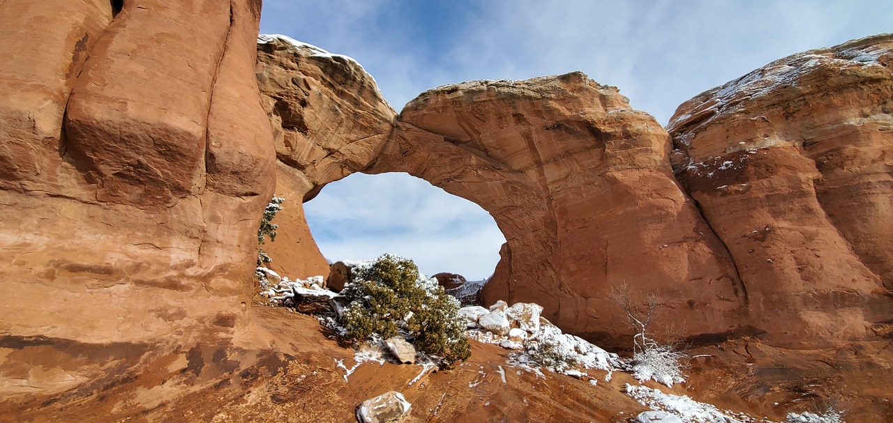 Hero image of Tunnel Arch in Arches National Park, viewed from the Devils Garden Trail with red sandstone fins and a clear desert sky.