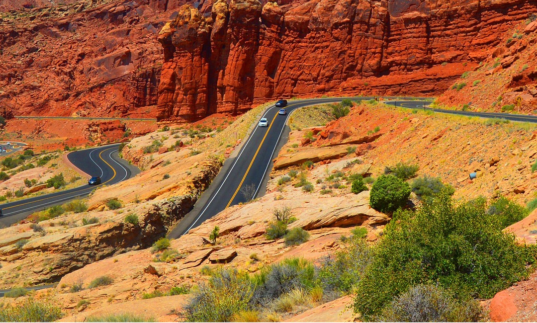 Scenic view of the winding entrance road to Arches National Park near Moab, Utah, surrounded by vivid red rock cliffs and desert terrain. Arches is open sort of.