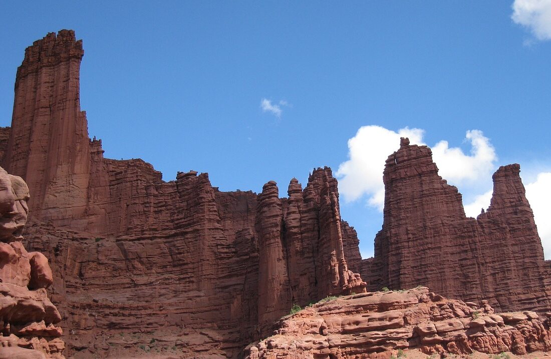 Dark red Cutler sandstone spires of Fisher Towers rising against the desert sky near Moab, Utah